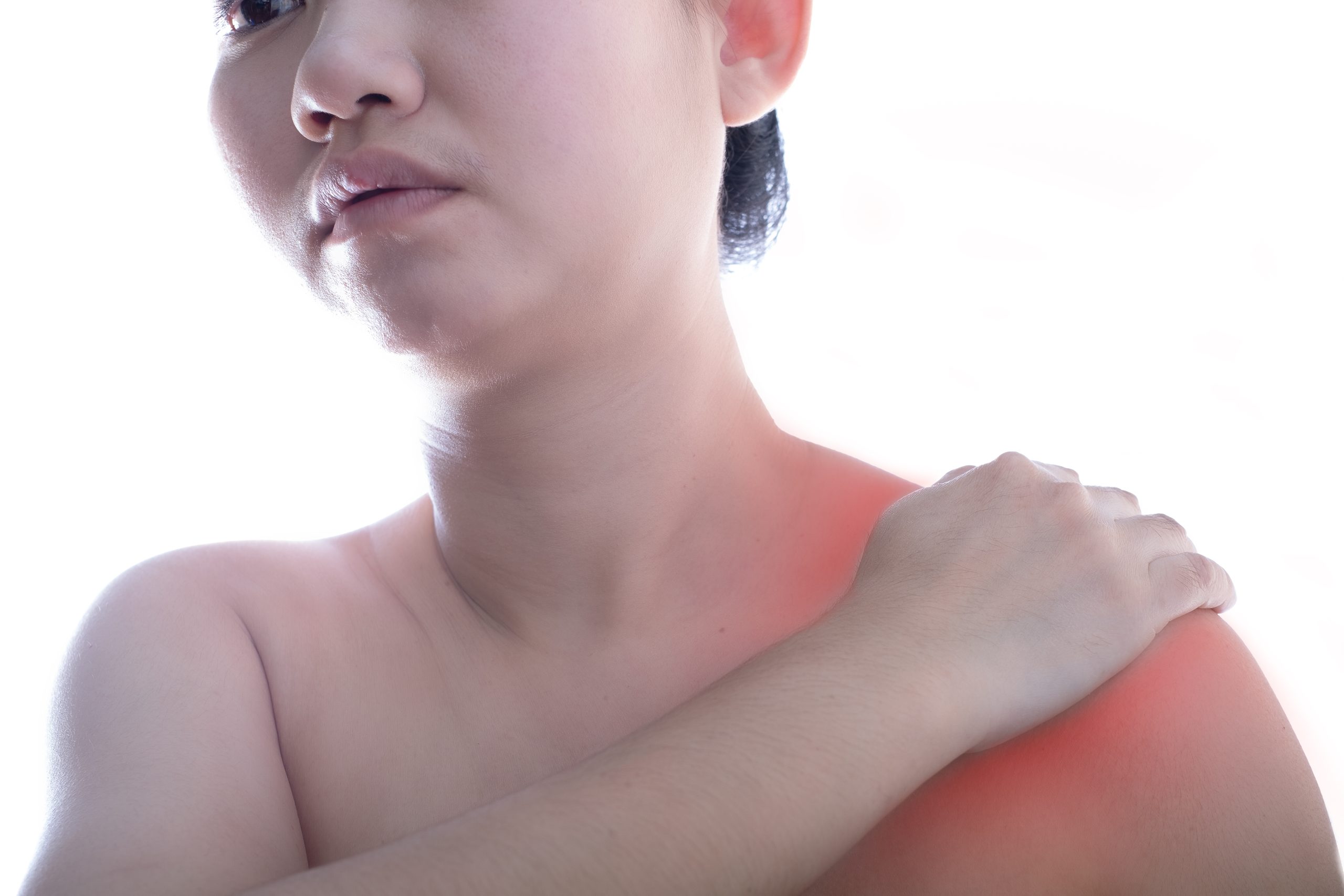 A person holds their shoulder, displaying an expression of discomfort. The shoulder area is highlighted in red, suggesting pain or injury, against a plain white background.