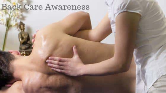 A person receives a back massage from another individual in a serene setting with a statue and flowers. "Back Care Awareness" is written at the top.