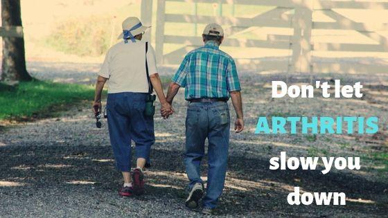 An elderly couple walks hand in hand on a gravel path, near a wooden fence, in a sunlit park. Text reads, "Don't let ARTHRITIS slow you down."