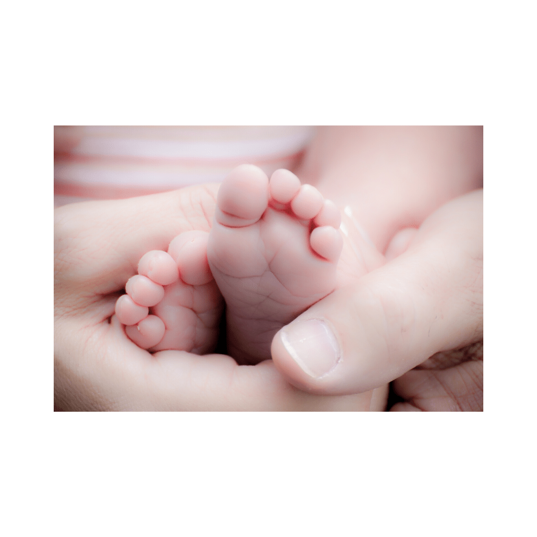 Tiny baby feet resting gently in an adult's hands, with a soft, blurred background, conveying warmth and tenderness.