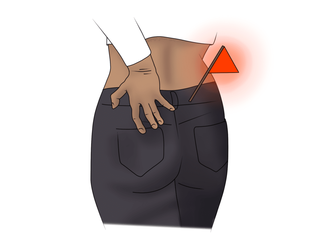 A person touches their lower back, where a small red flag is inserted, symbolizing pain or warning, against a close-up view of their jeans.